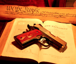 A gun on the Bible with the Constitution. Source San Diego Free Press